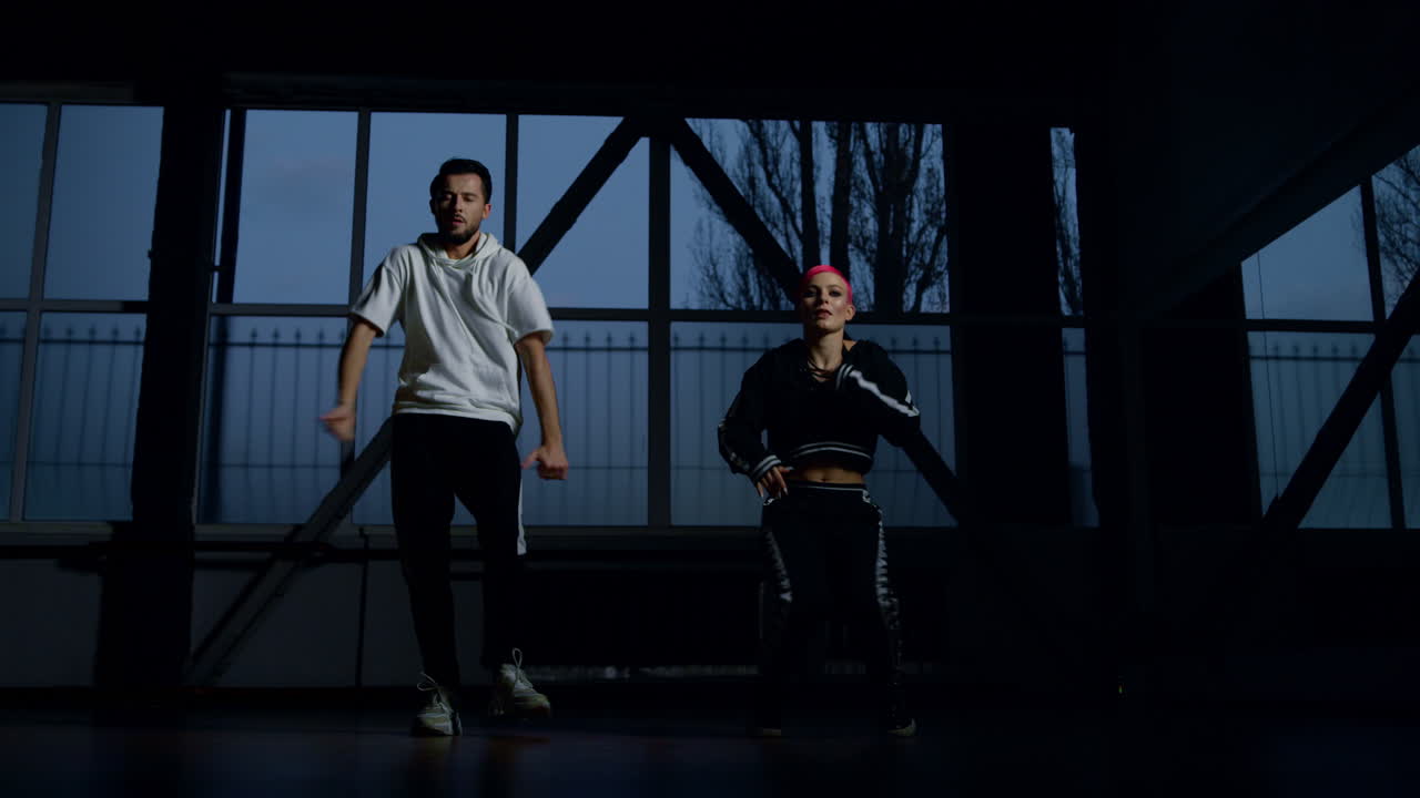 jóvenes bailarines aprendiendo pasos de hip hop en un estudio oscuro. una pareja bailando en el interior.