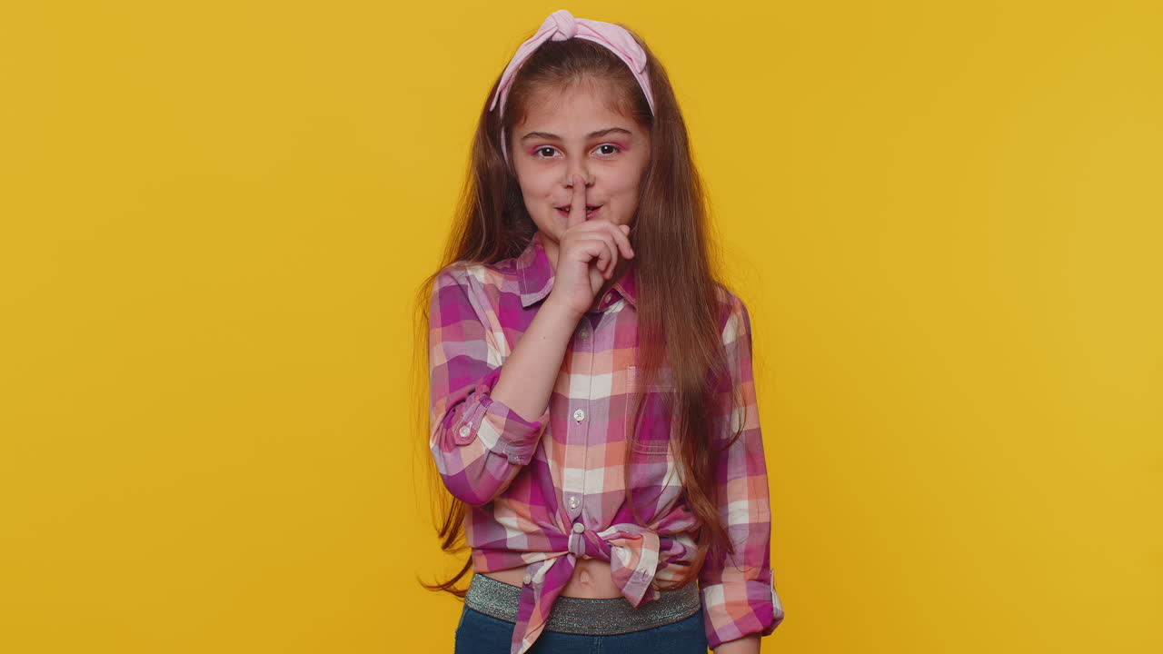 Preteen child girl presses finger to lips makes silence hush sign do not tells gossip secret, quiet