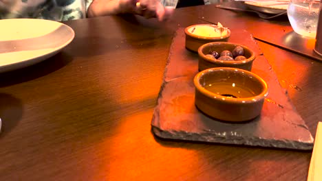 mujer cortando mantequilla para esparcir en el pan en un restaurante europeo tradicional
