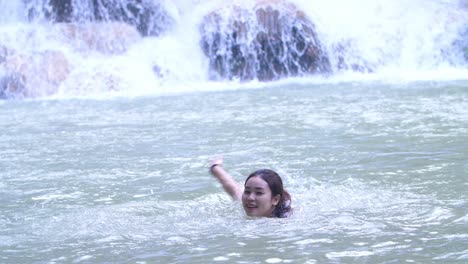 woman swimming in a waterfall river