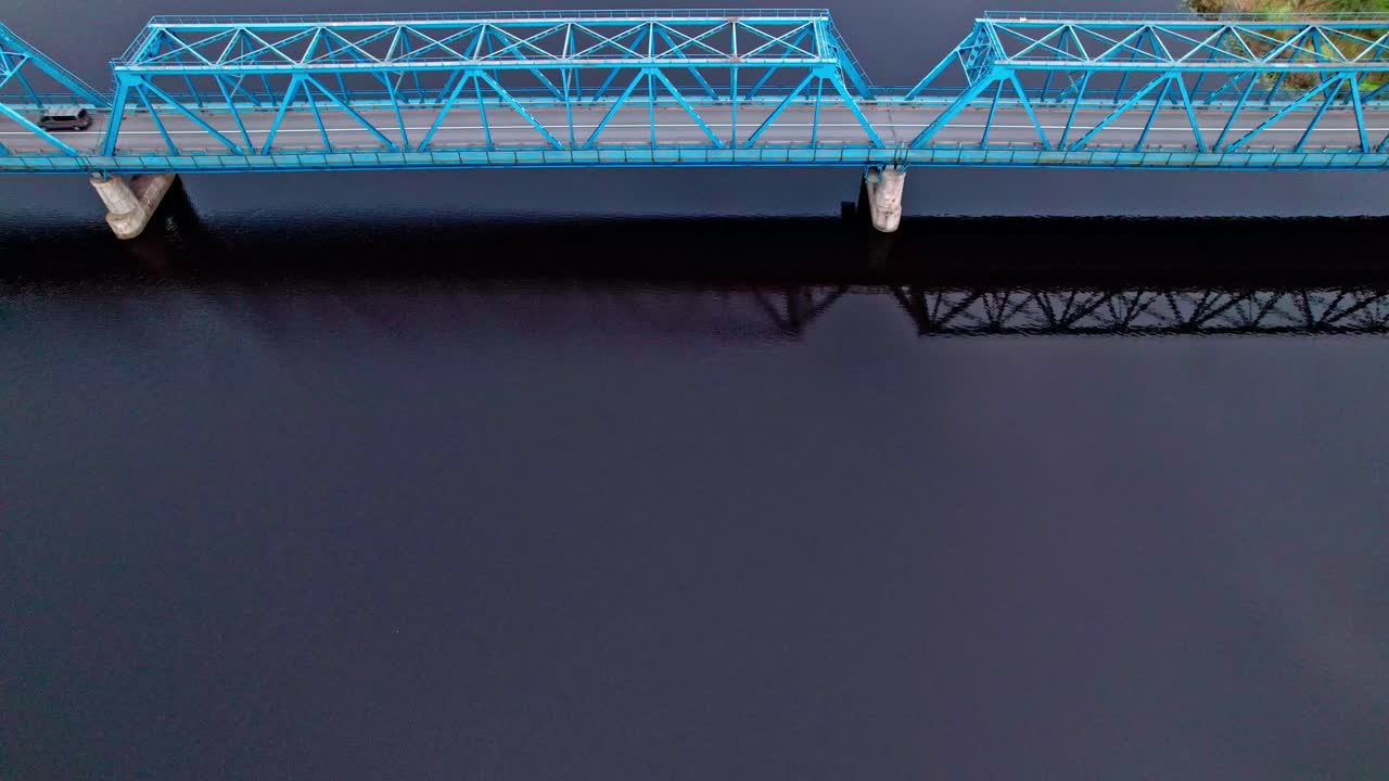 Blue bridge spans dark waters in Latvia's scenic aerial view