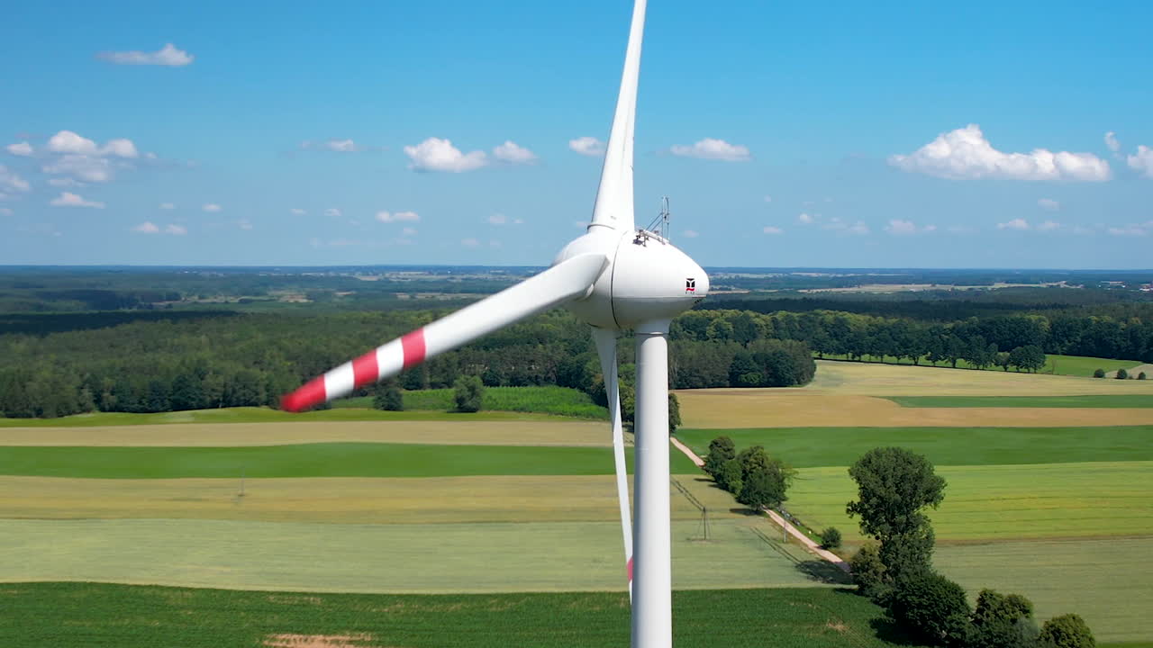 близкий вид вращающейся ветровой турбины в сельской местности с пышными сельскохозяйственными угодьями