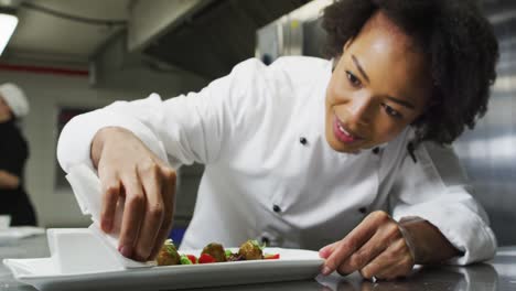 Portrait-of-african-american-female-chef-garnishing-dish-looking-at-camera-and-similing