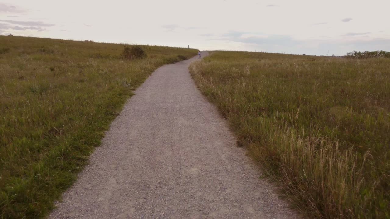 niña, niño pequeño, montando en bicicleta cuesta arriba, en el parque nose hill, calgary, alberta, canadá