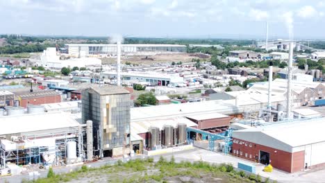 Industrial-warehouse-power-plant-refinery-buildings-under-smokestack-wasteland-aerial-view-reverse-dolly-left