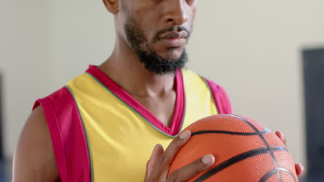 hombre afroamericano enfocado sosteniendo una pelota de baloncesto en el interior