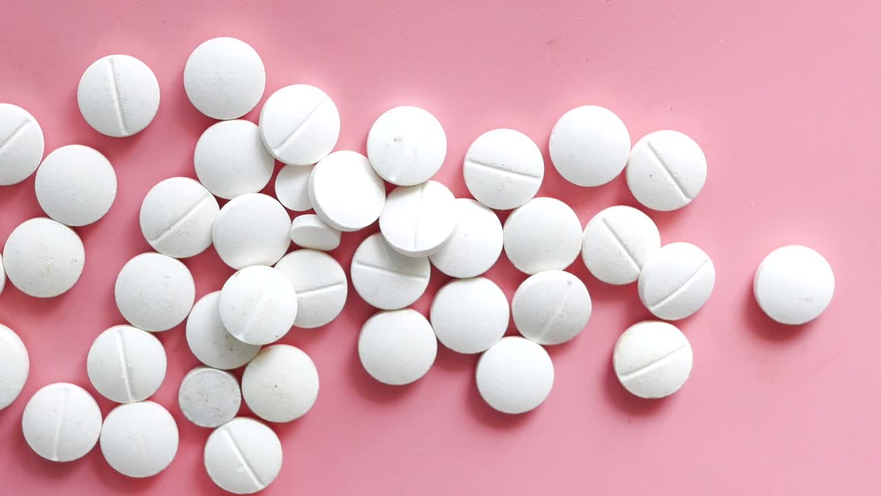 White Round Pills on a Pink Surface
