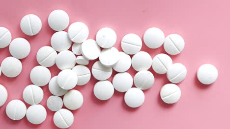 white round pills on a pink surface
