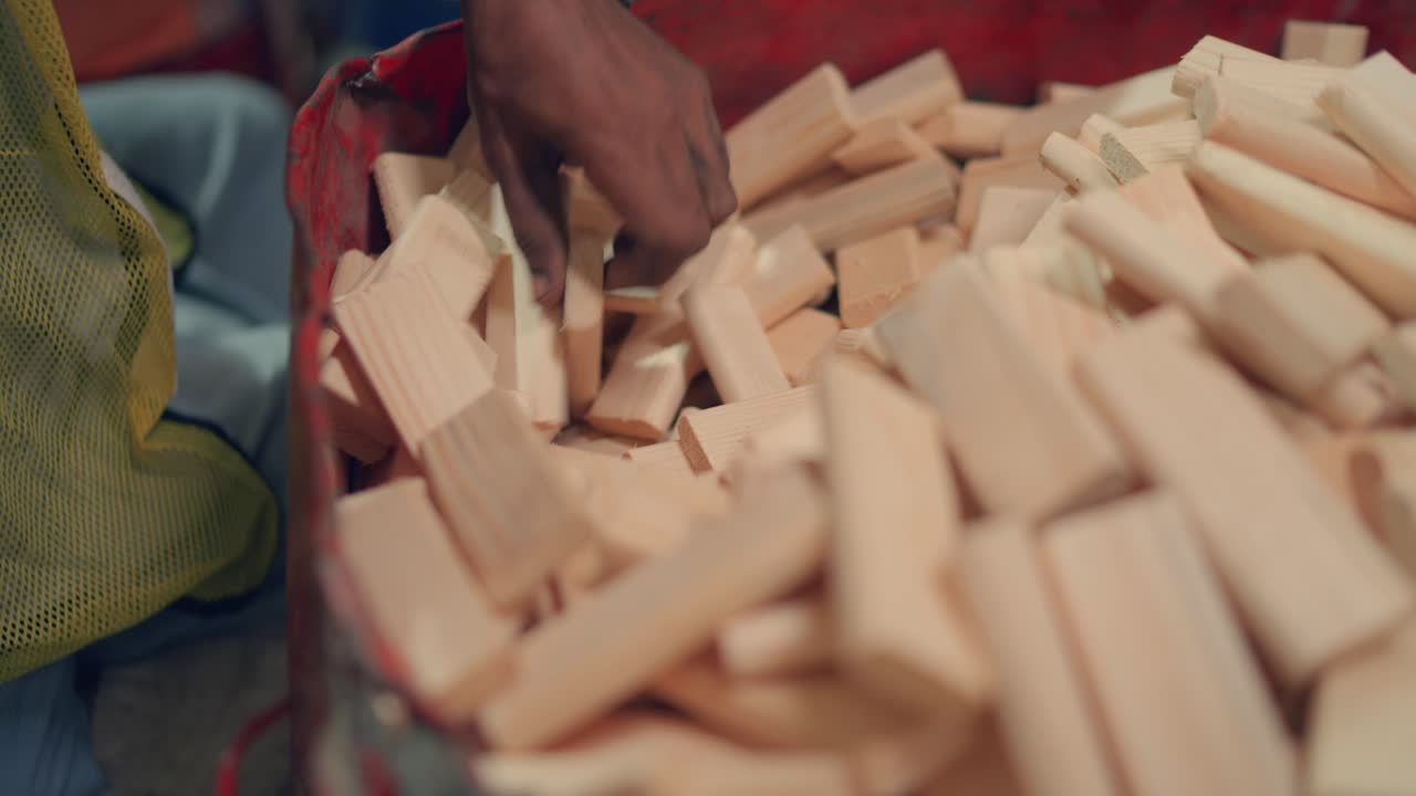 Worker's Hand Picking Up Wooden Blocks from Container