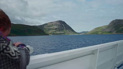 woman takes a video of the mountains from a sailing boat