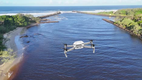 aerial drone footage capturing a river flowing into the ocean, showcasing lush greenery and dynamic water movement