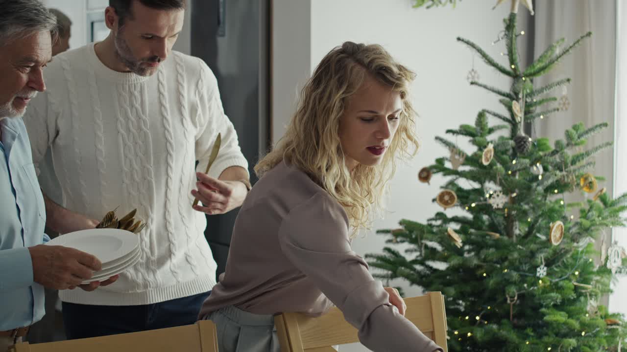 старший мужчина с взрослой дочерью готовит стол к рождеству.