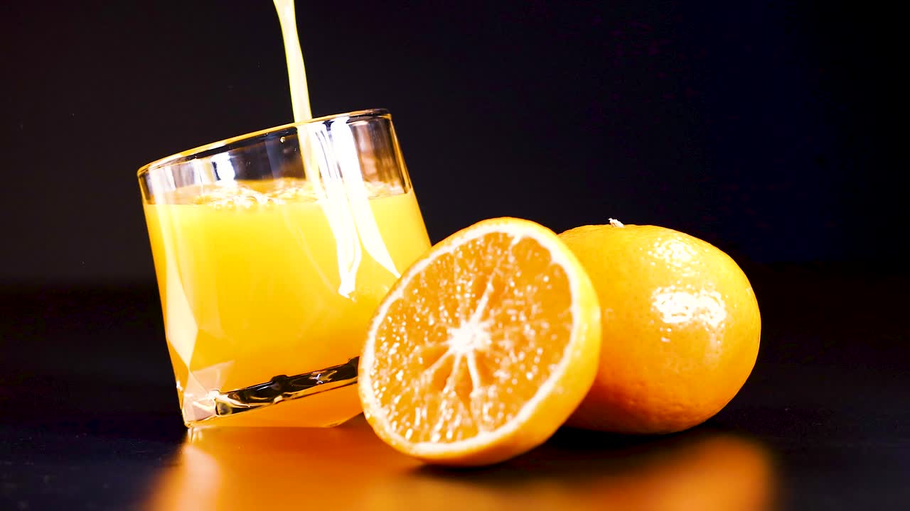 Succo che si versa in un bicchiere con arance nelle vicinanze