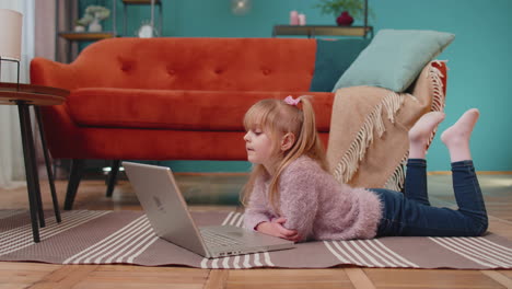 little school kid girl use laptop computer learning reading online education lessons alone at home