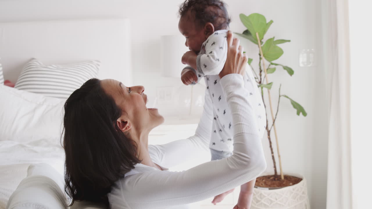 Millennial African American mother lifting her baby and smiling to him