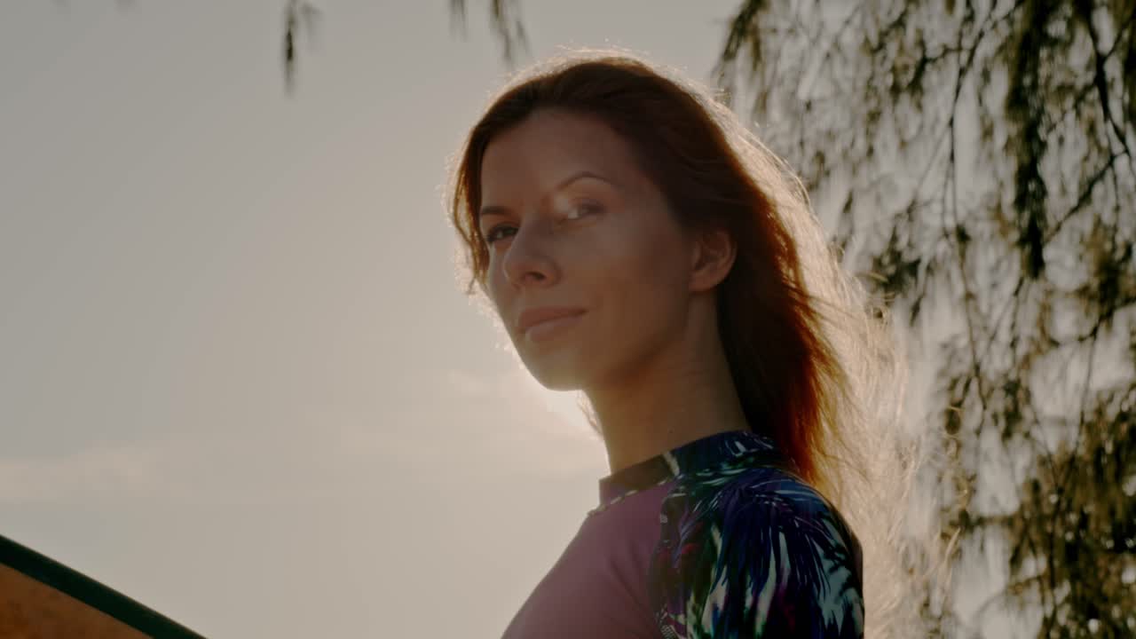 mujer con tabla de surf al atardecer