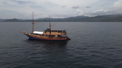 Aerial-View-Of-Wooden-Boat-With-Tourists-Sailing-On-The-Coast-Of-Bali,-Indonesia