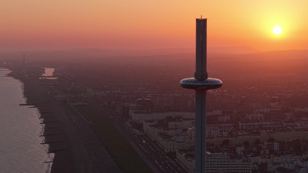 Drone orbit of Brighton’s i360 Tower during golden hour, showcasing warm light, the cityscape in the background, and the modern coastal architecture