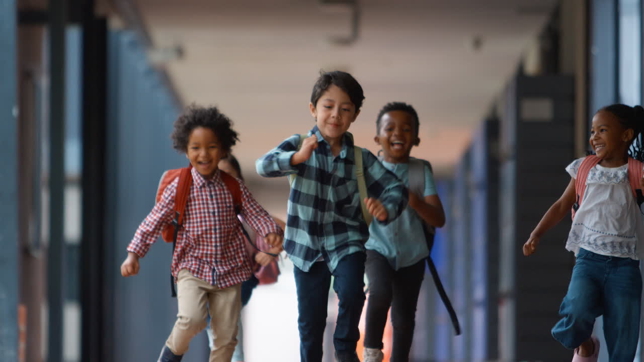 Group Of Multi-Cultural Elementary School Pupils Running Along Walkway Outdoors At School