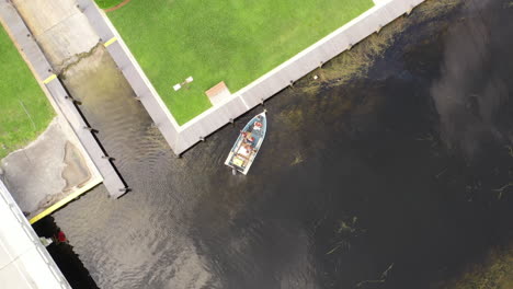 an aerial, top down drone shot over a boat in a canal, the camera is looking straight down and pan left