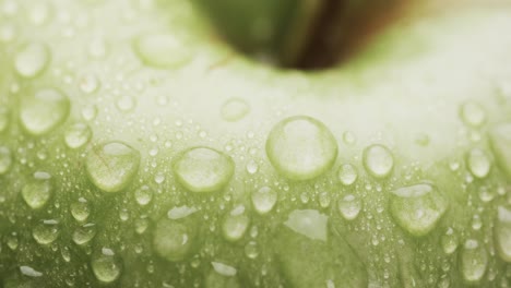 micro video of close up of green apple and water drops with copy space