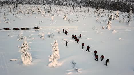 Drone-view-of-snowshoe-walking-in-Saariselka,-Lapland,-Finland