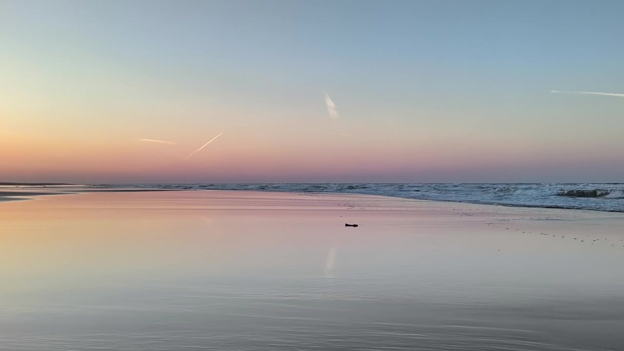 Fredfyldt solnedgang over rolige havbølger ved lavvande