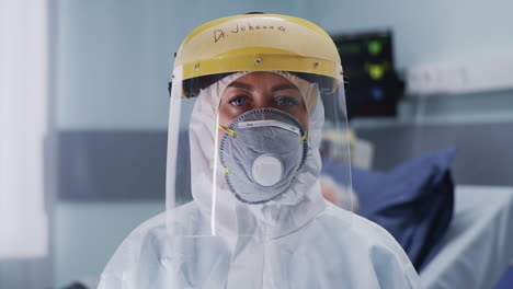 medical practitioner in hazmat suit looking at camera female doctor in mask and face shield looking at camera during work in covid hospital