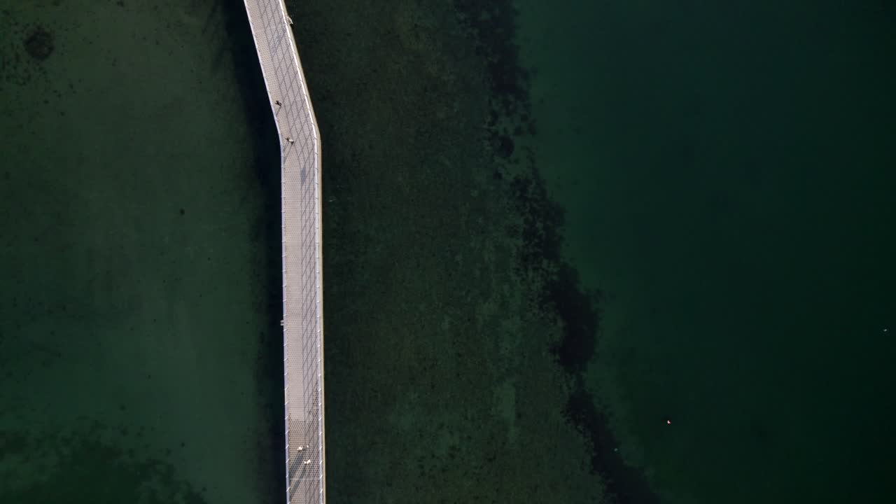 People walking through a bridge come from and go to one side to the another. they look peaceful, calm and steady. Walking with people around you is a happy moment.