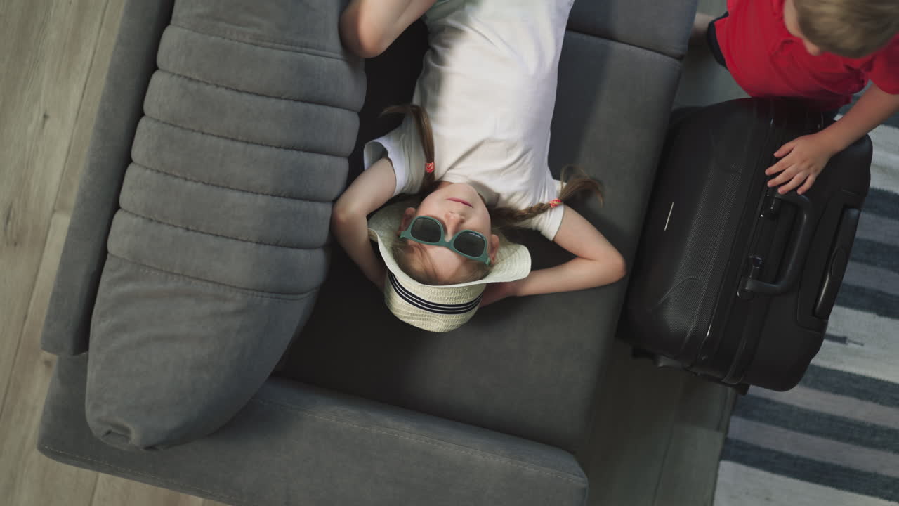 el niño juega con el juguete mientras la hermana se relaja en el sofá