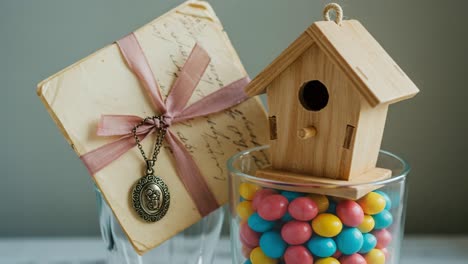 a charming display of nostalgia: a handmade wooden birdhouse and colorful candy in glass containers accent a vintage letter, perfect for home decor