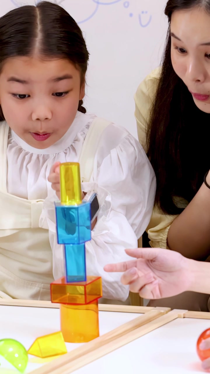 Children and teacher explore magnetic blocks and rolling balls in bright classroom, laughing and learning.