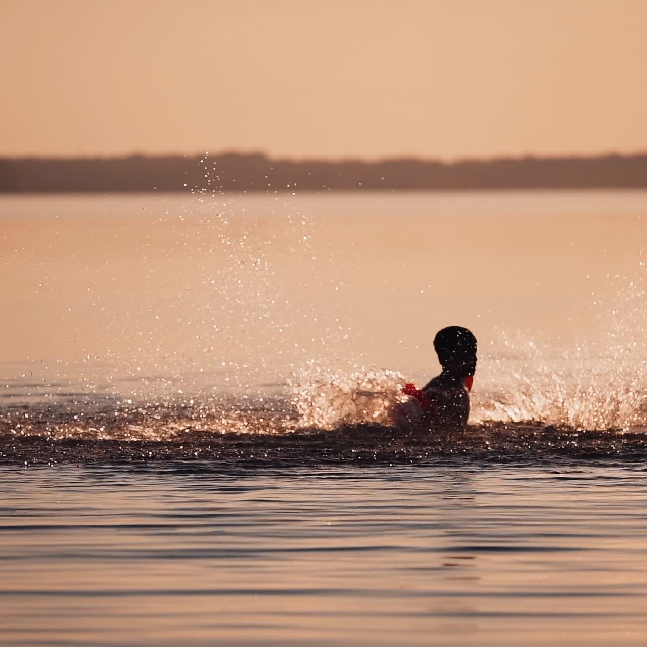 Silhouette of boy at sunset in the river. Silhouette of a child playing splash water in river