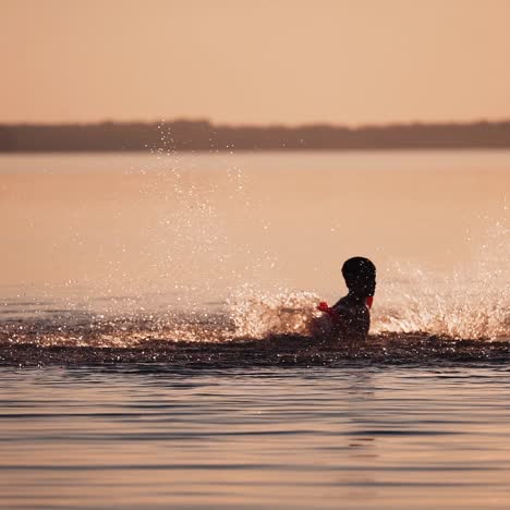 silhouette of boy at sunset in the river. silhouette of a child playing splash water in river