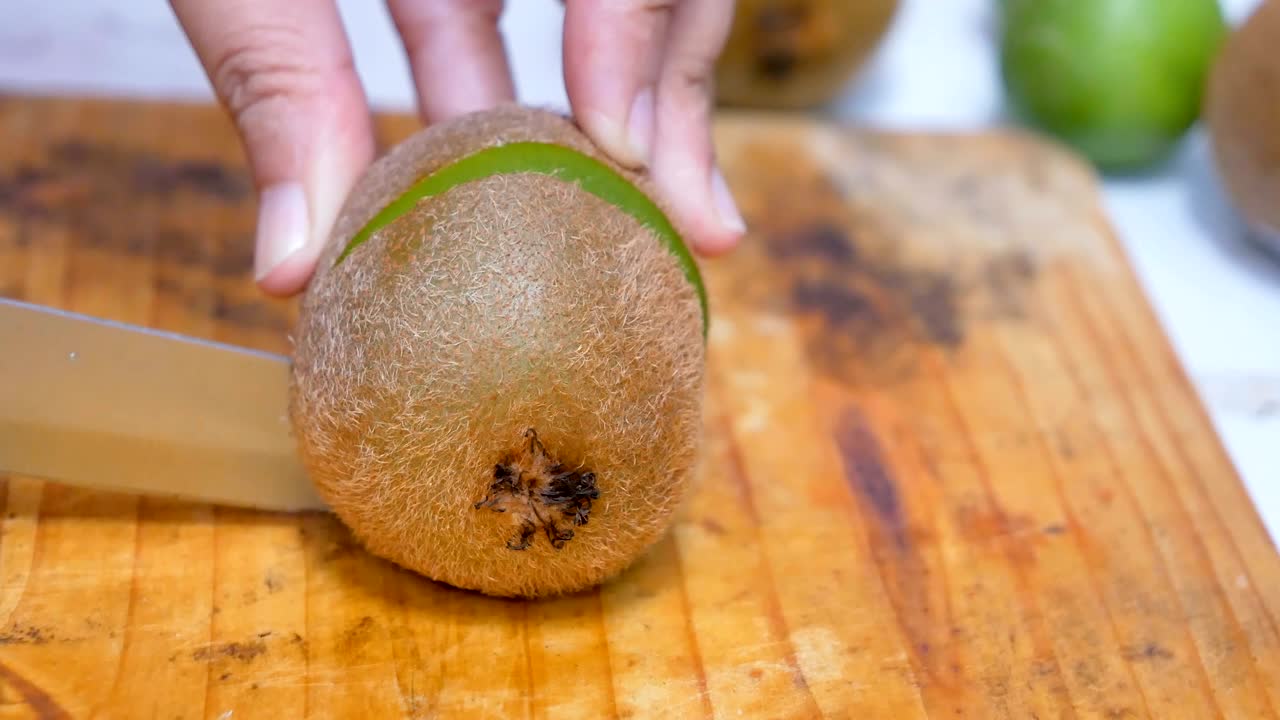 cortando el kiwi por la mitad en la tabla de cortar en la cocina.