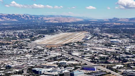 aerial view of san jose international airport with surrounding urban landscape and distant mountain ranges under a clear sky in silicon valley, california