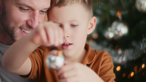 young boy playing with christmas bauble smiling at dad