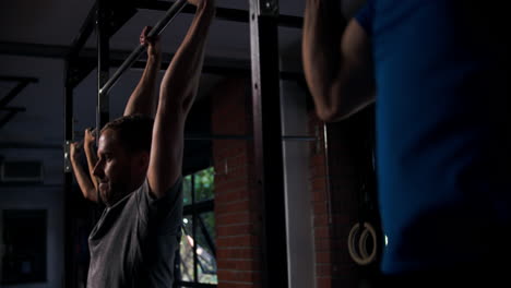 Three-people-doing-chin-up-exercises-on-a-pull-up-bar-in-a-gym