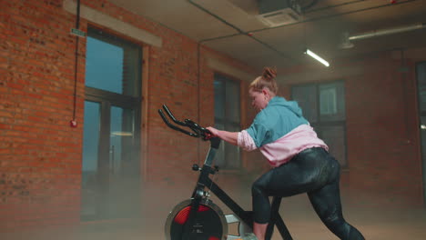 Mujer-Caucásica-Sana-Haciendo-Ejercicio-En-Bicicleta-Estacionaria-En-Bicicleta-En-El-Gimnasio,-Cámara-Lenta