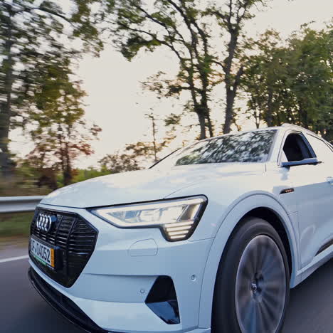front view of a luxury car moving on the road in daylight. new electric car audi e-tron driving on the highway in summer.