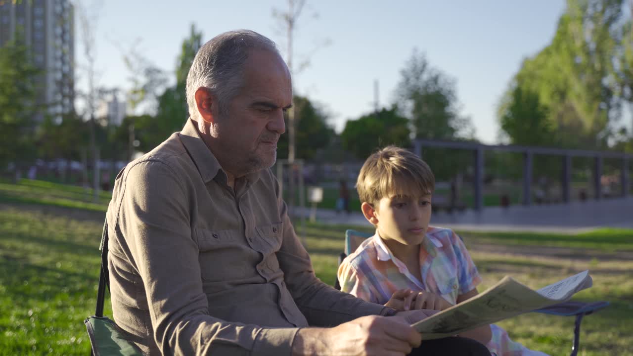 손자가 신문을 읽고 있는 밖에서 앉아 있는 노인.