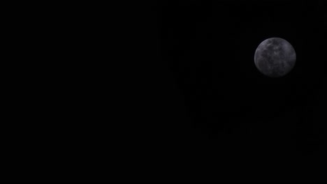 Telephoto-Shot-of-Moon-rising-with-a-dark-background-and-clouds-in-front-of-the-moon