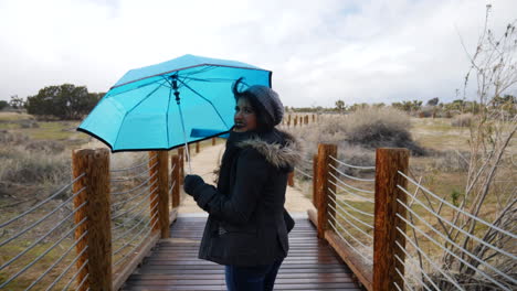 Una-Mujer-Bonita-Cruzando-Un-Puente-Con-Un-Paraguas-Azul-Durante-Una-Tormenta-De-Lluvia-En-Cámara-Lenta-Con-Mal-Tiempo