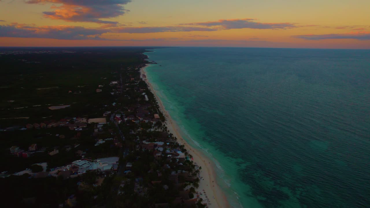 toma de drones del mar verde, con la playa de arena de akiin y las casas entre los árboles, al atardecer