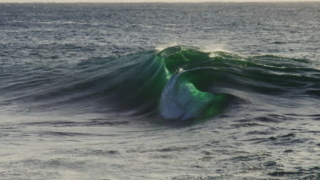 large swell forms across deep water with blue green gradient and soft foamy details near crest