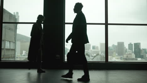 silhouetted business people walking in front of a cityscape