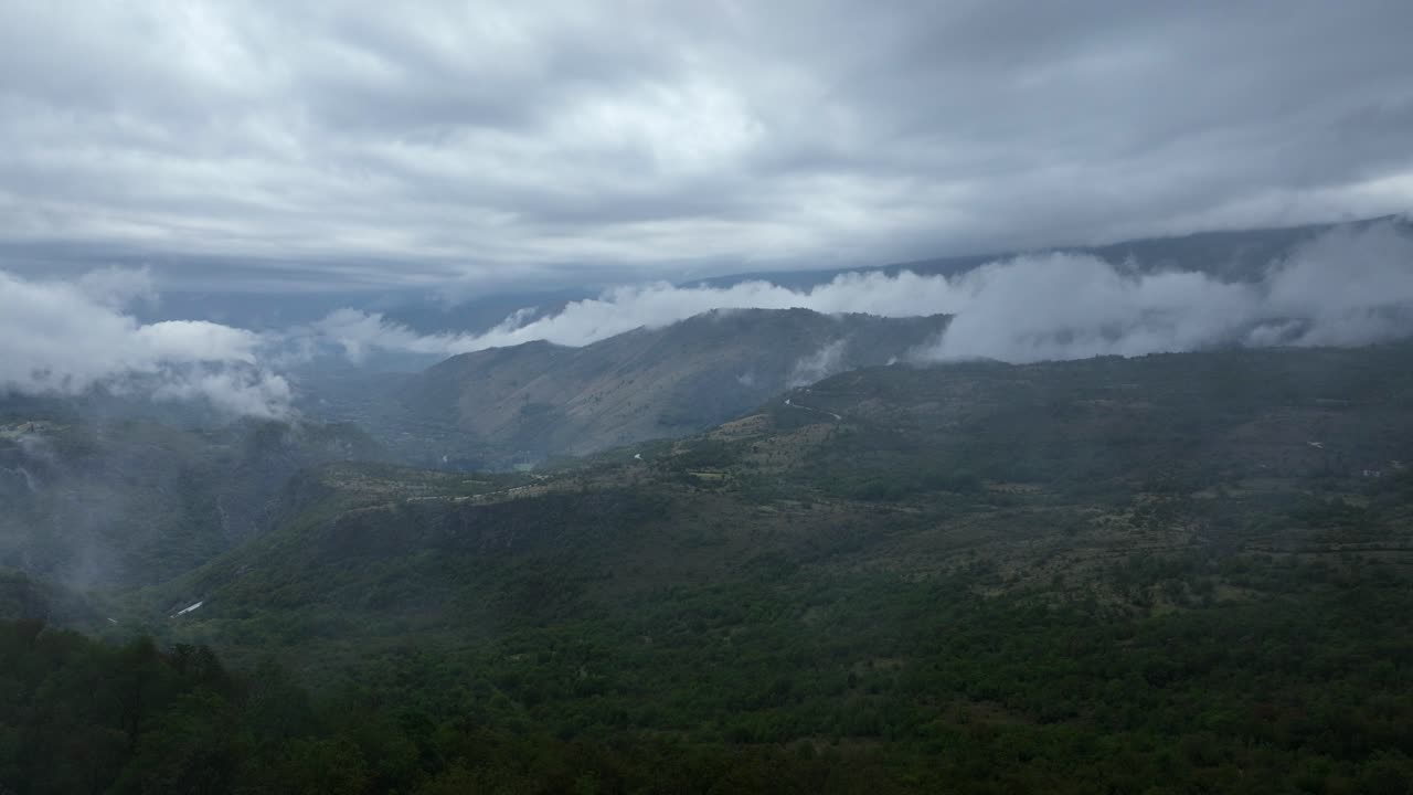 Aerial view of dark cloud covered mountain valley with fog rolling over ridges near Cetinje, Montenegro