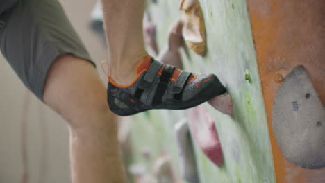 close-up of feet shod in shoes for rock climbing overcome obstacles on the climbing wall.