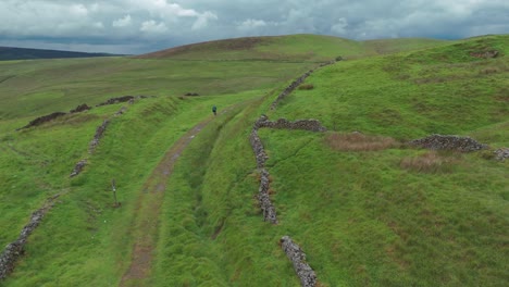 forward drone shot of a trekker exploring peak district national park during cloudy day in england