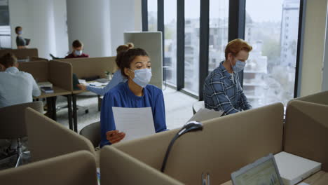 businesswoman looking at documents. professionals in masks talking in office